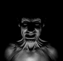 Stylish dark portrait of feared adult caucasian man who wrinkles his face. Fear and disgust concept. Black and white shot, low key lighting.