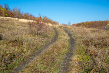 Fototapeta na wymiar Dirt road on the autumn slope of a ravine