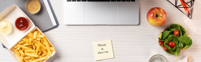 top view of laptop, note with inscription make a choice and junk food with healthy food on table in office