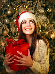 Happy dreamy woman with gift at home on New Year tree decorations