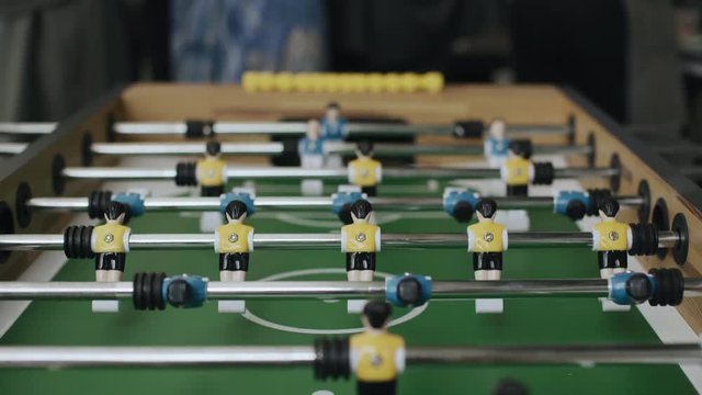 Friends having fun together playing foosball. Colleagues playing table football on break. Office people enjoying table soccer game. Close up of table football kicker game, 4k, handheld