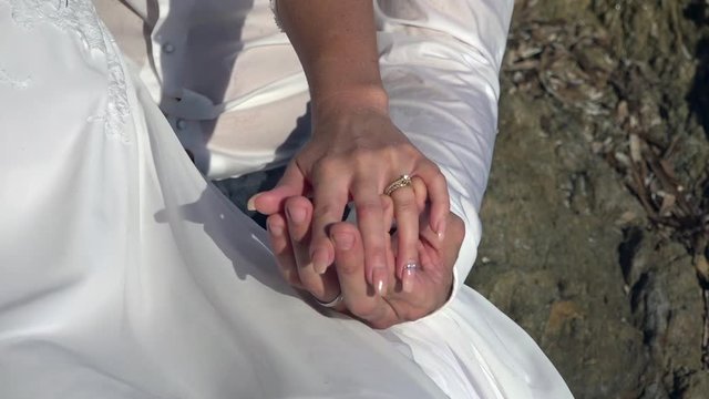 Hands of young bride and groom playing with alliances