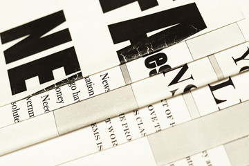 Newspapers. Headlines and articles shown partially in a stack of daily papers with news 