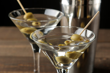 Martini in a glass wineglass with green olives on a skewer on a brown wooden table. cocktails. bar
