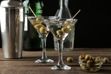 Martini in a glass wineglass with green olives on a skewer on a brown wooden table. cocktails. bar