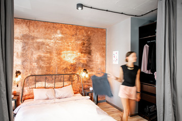 Modern loft bedroom intreior with bright copper wall and motion blurred woman walking with clothhes