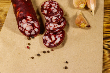 Sliced salami sausage on brown paper on wooden table
