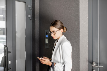 Young businesswoman waiting with phone near the entrance of the residential building