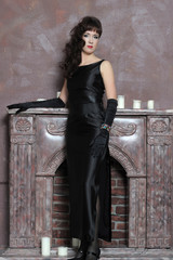 t brunette in a black dress and gloves by the fireplace