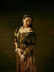 Girl in medieval beautiful dress or costume of the countess at dark studio.