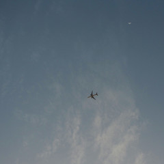 Flying plane high in the sky, a small silhouette against clouds