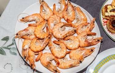 Freshly cooked prawns and ready to eat, placed on a plate on top of a table