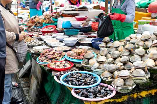 Seafood shop at Jagalchi market in Busan, South Korea, sells many kinds of fresh scallops, shells and clams to customers for cooking at home.