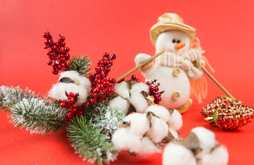 spruce branch, cotton branch, red berries, Christmas decor, red background, toy snowman in Golden hat