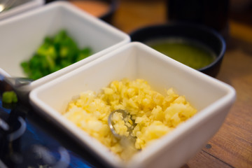 Slice of garlic on white bowl for topping sauce