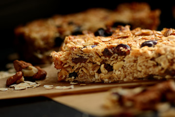 Homemade granola bars with nuts and cranberries over black background