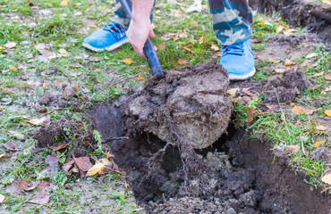 Man digging a ditch with a shovel in autumn