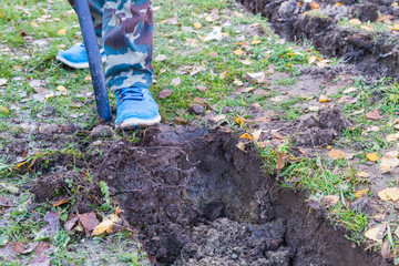 Man digging a ditch with a shovel in autumn