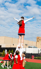 Cheerleaders holding teammate in the air outside