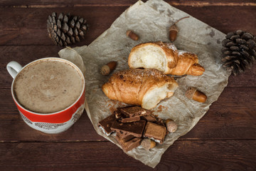 Coffee and fresh croissant for breakfast on rustic wooden table. Chocolate croissant with cappuccino
