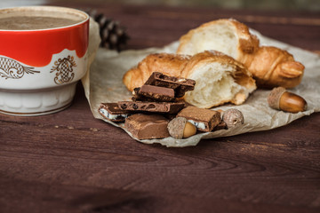 Coffee and fresh croissant for breakfast on rustic wooden table. Chocolate croissant with cappuccino