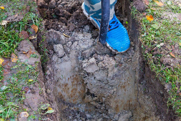 Fototapeta premium Man digging a ditch with a shovel in autumn