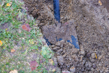 Man digging a ditch with a shovel in autumn