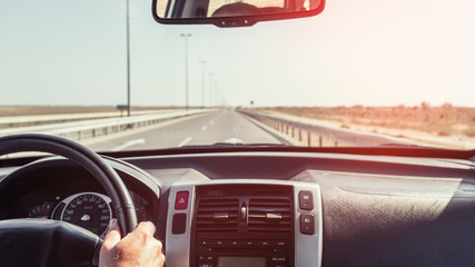 Driver hand on the steering wheel of a car, dashboard