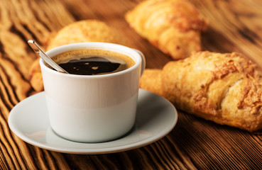 Cup of coffee with croissants on a wooden table