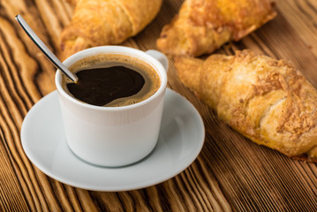 Cup of coffee with croissants on a wooden table