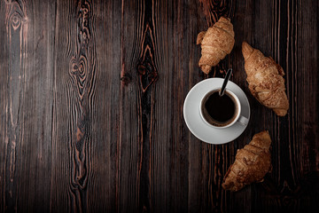 Cup of coffee with croissants on a wooden table