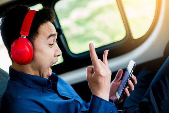 Relax Young Man Wearing Shirt On A Car Listening To Music On A Smartphone With Red Headphone.