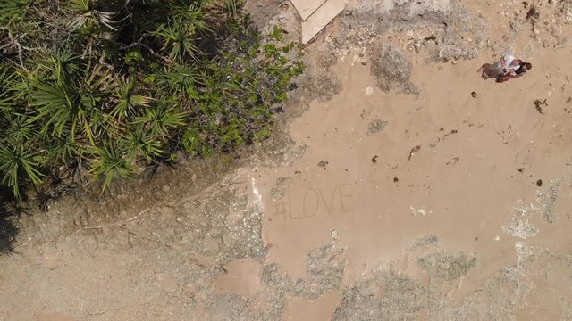 Aerial view of a wild beach with a text love on a sand. Hashtag love. Bali island.