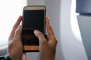 woman traveler using smartphone in airplane. passenger holding mobile phone in aircraft. travel & connection