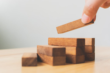 Hand arranging wood block stacking as step stair. Ladder career path concept for business growth success process