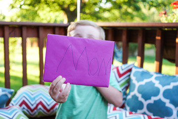 Child handing a Mother's Day card to his mom