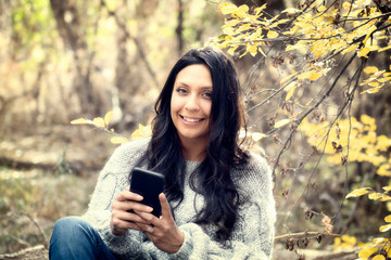 Beautiful Young Hispanic, American Indian, Multi-racial Woman Checking Messages & Taking Selfies with Cell Phone Outside on a Fall Day
