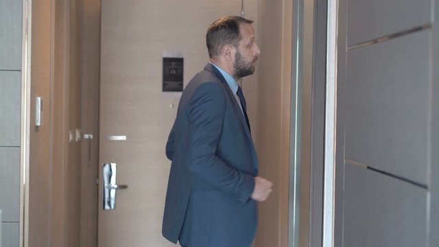 Businessman returns back to his hotel room and looks at oneself in the mirror 