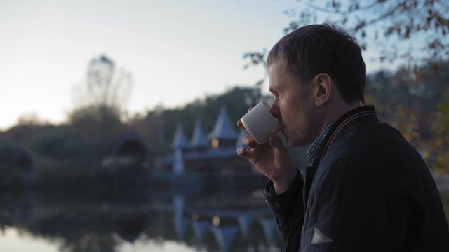 Close-up, Sad Man Drinks Tea in the Autumn Park Near the Lake