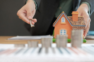 realtor agent with coins stack house model & key. saving money for buying real estate property