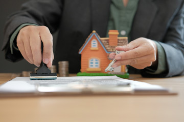 real estate agent with house key stamping approved on mortgage loan contract agreement document