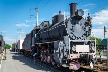 Plakat Old steam locomotive beside a railway station platform. Retro train.