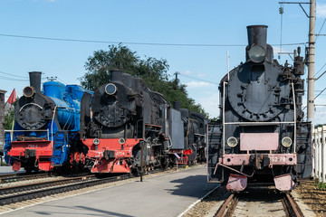 Old steam locomotive beside a railway station platform. Retro train.