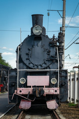 Old steam locomotive beside a railway station platform. Retro train.