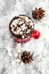 red cup of drink and  marshmallow on snow-covered snow-covered wooden background