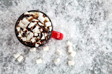 Obraz na płótnie Canvas red cup of drink and marshmallow on snow-covered snow-covered wooden background