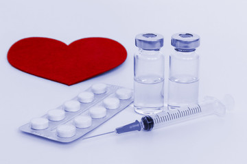 Syringe, vials, tablets and red heart . Cardiology and heart deseases concept