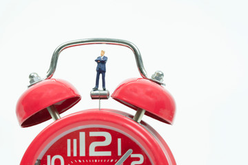 Miniature businessman with red alarm clock