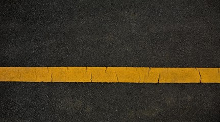 Fototapeta premium Yellow paint line on black asphalt. space transportation background