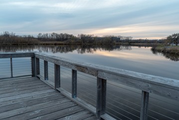 Naklejka premium Dramatic view of still lake water from a wooden dock on a misty Autumn evening